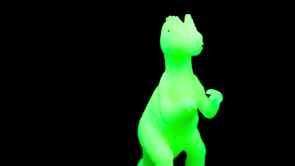 Green Toy Dinosaur Turning Agaisnt Black