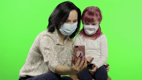 Mother, Daughter Wearing Medical Mask Holding Smart Phone Talking on Video Call