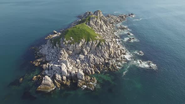 Aerial View of a Beautiful Small Rocky Island Surrounded By Clear Blue Sea