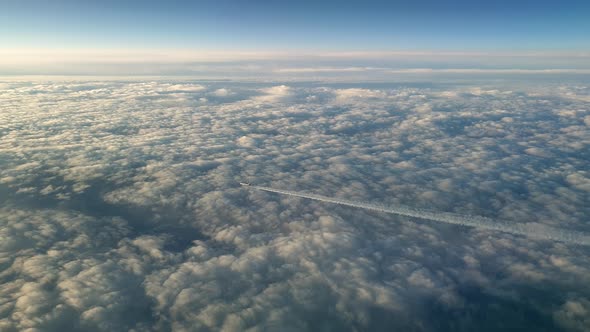 Incredible view from the cockpit of an airplane flying high above the clouds leaving a long white co