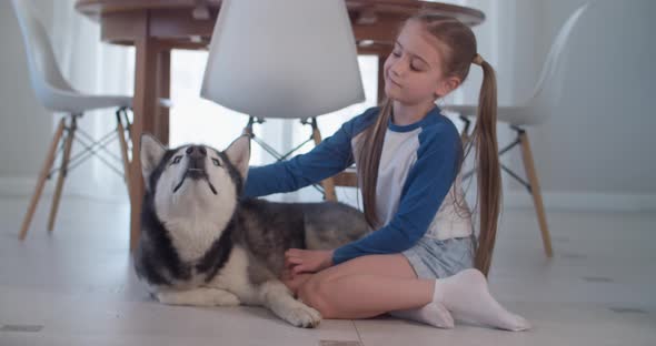 Girl Stroking Her Purebred Dog While Lying on the Floor in a Modern Apartment