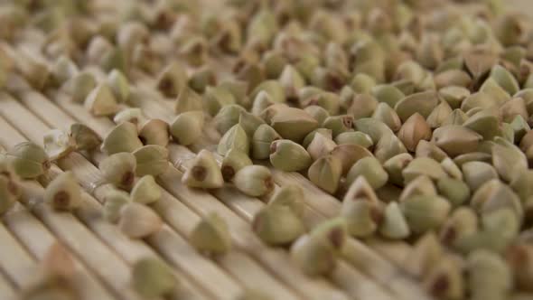 Uncooked green buckwheat is poured in slow motion on a bamboo texture mat