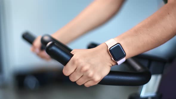 Closeup Female Hands Holding By Handle of Exercise Bike During Cycling