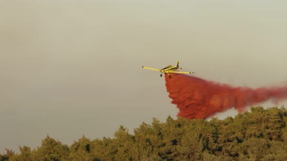 Fire fighter plane drops fire retardant on a forest fire in the hills