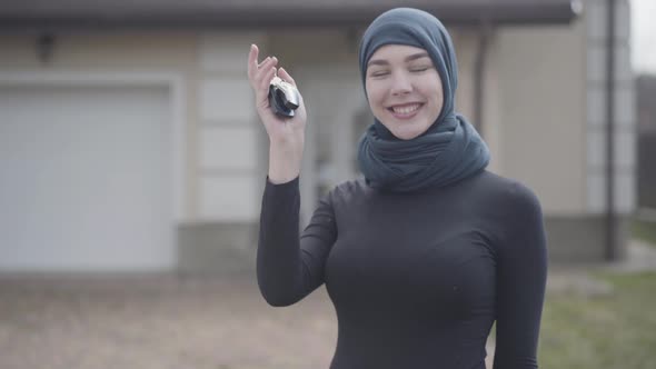 Portrait of Independent Smiling Young Muslim Woman Holding and Waving Car Keys Wearing Traditional