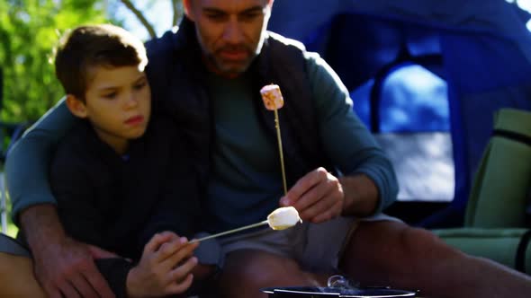 Father and son roasting marshmallows outside the tent