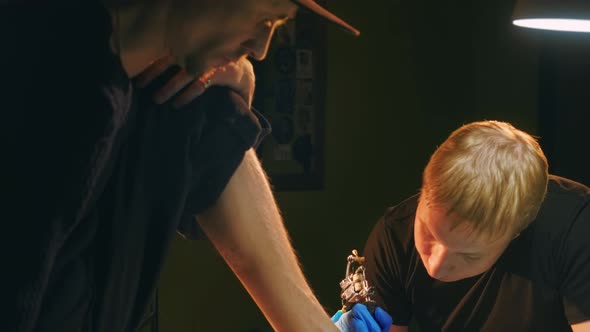 Feet Tattoo Pattern Face of Focused Tattooist Artist with Coil Needle Machine