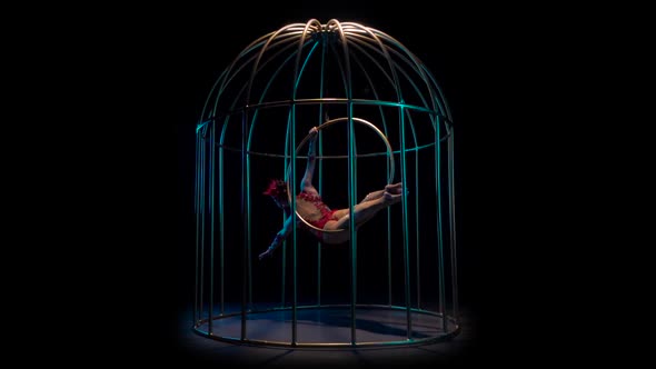 Aerial Gymnastics Rotates on a Hoop in a Cage. Black Background. Slow Motion