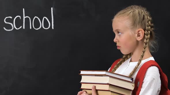 Naughty Girl Holding Books Showing No Gesture, School Word on Blackboard