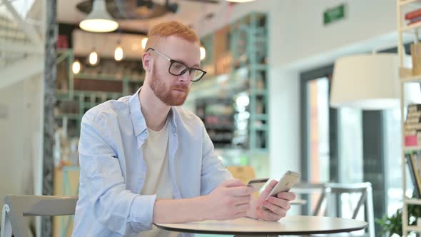 Online Payment Success on Phone By Redhead Man in Cafe 