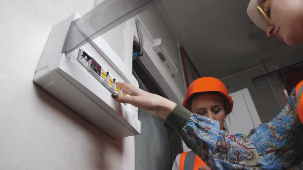 Two Women Inspectors in Helmets Check Operability of Electrical Systems