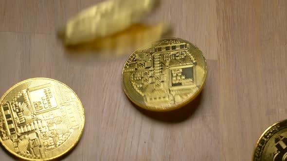 Several golden bitcoins falling in slow motion on table,close up shot