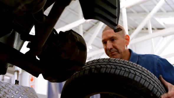 Mechanic fixing car wheel in garage 4k