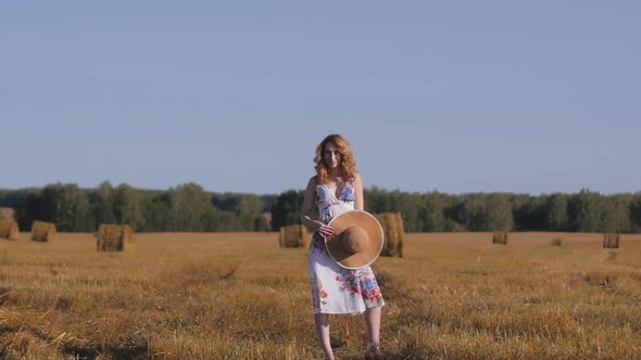 Young Redhead Woman with Wicker Basket Walks in the Field Enjoying Nature