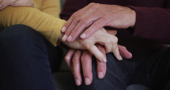 Mid section of senior caucasian couple sitting and holding hands