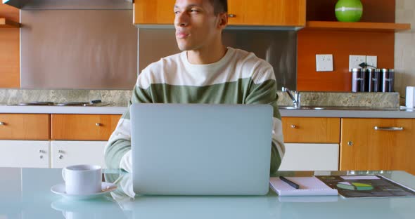 Man using laptop in kitchen at home 4k