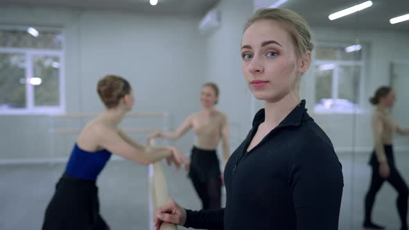 Inspired Gorgeous Young Caucasian Ballerina Posing at Barre in Dance Studio with Blurred People