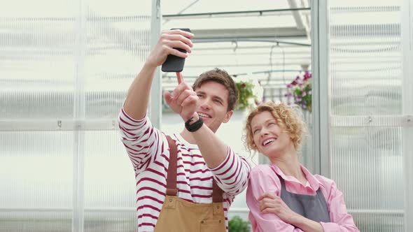 Couple of Gardeners Making Selfie Photo Standing Together with Plant in the Greenhouse