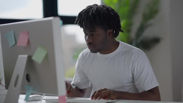 Portrait of Busy Young Man Typing on Keyboard Looking at Monitor Screen