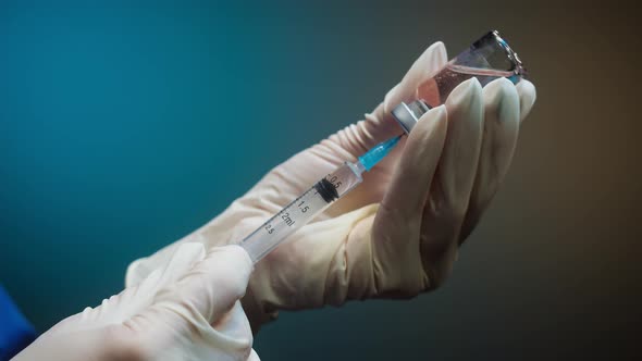 Doctor Filling Syringe with Solution on Blurred Background