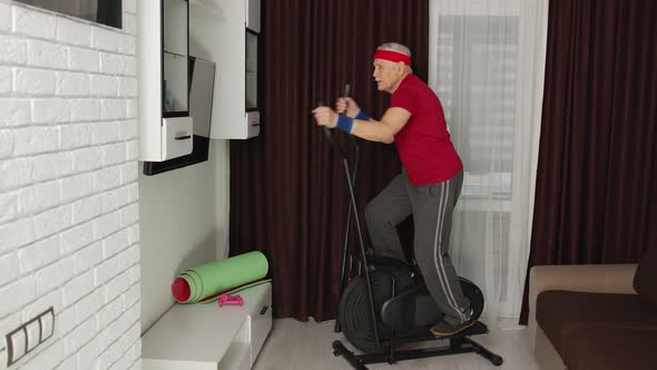 Active Healthy Senior Old Mature Man in Sportswear Using Orbitrek Training Cardio Workout at Home