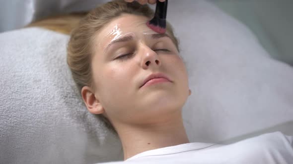 Worker of Beauty Salon Putting Moisturizing Mask on Face of Girl, Femininity