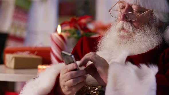 Santa Claus using cell phone, closeup alt