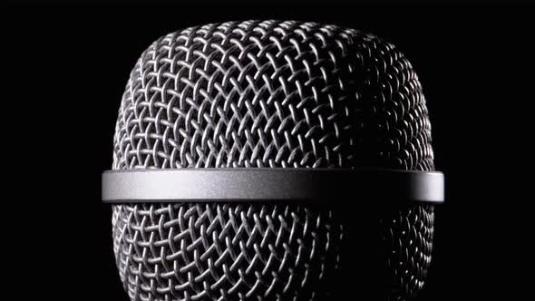 The Microphone Rotates on a Black Background. Dynamic Microphone Grid Spins Close-up