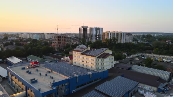 Aerial View of Blue Photovoltaic Solar Panels Mounted on Industrial Building Roof for Producing