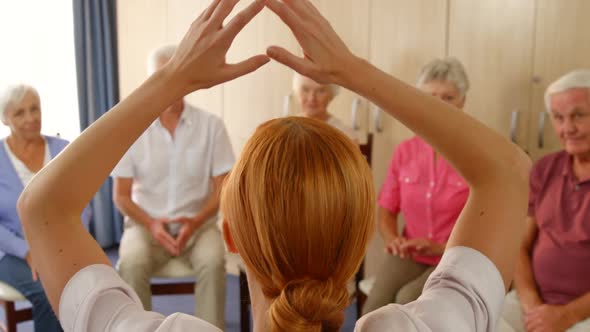 Therapist assisting group of senior people with exercise
