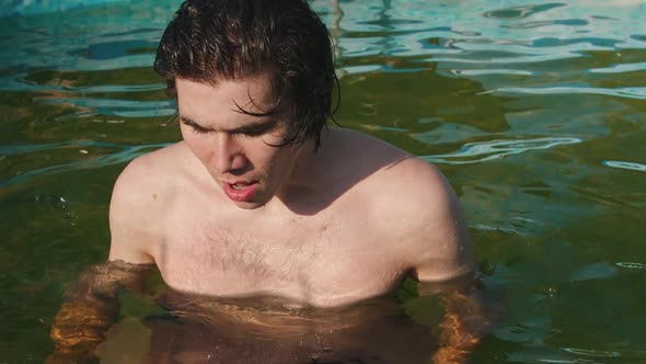 Young Man Dives Under the Water in the Inflatable Pool