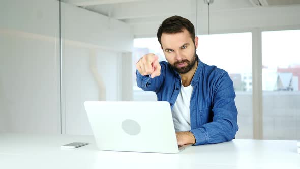 Man Pointing at Camera Sitting in Office Direction