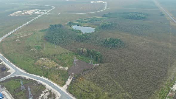 The Drone Flies to an Untouched Lake in the Taiga Around the Lake Power Lines and the Road