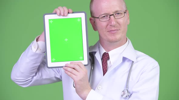 Happy Mature Bald Man Doctor Showing Digital Tablet