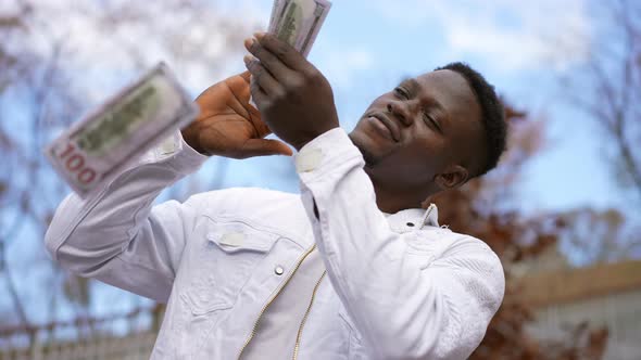 Satisfied Smiling Man Scattering Money Standing in Autumn City Park