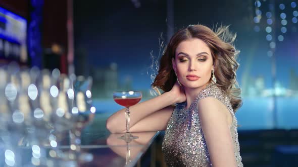 Medium Shot Portrait of Fashionable Sexy Woman Sitting at Bar with Cocktail During Party