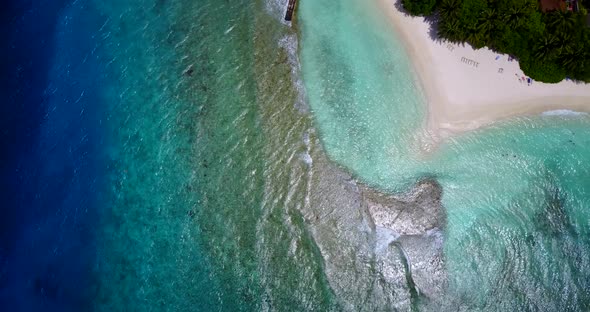 Beautiful fly over tourism shot of a sandy white paradise beach and blue ocean background 