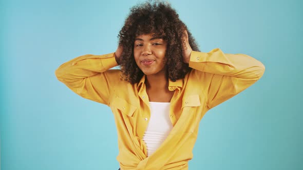 Darkskinned Woman Putting on Headphones Smiling Listening to the Music and Dancing While Posing on