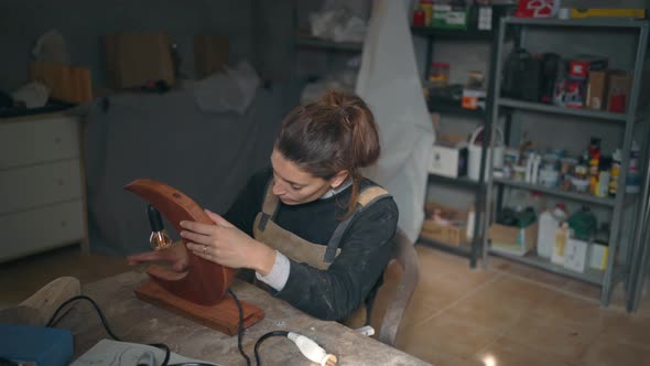 Craftswoman checking quality of wooden lamp