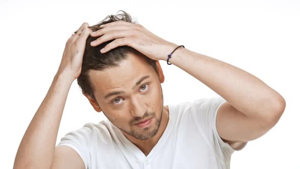 Young Handsome Man Styling Hair Looking at Camera Over White Background