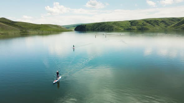 People Ride on SUP Board in the Mountain Lake