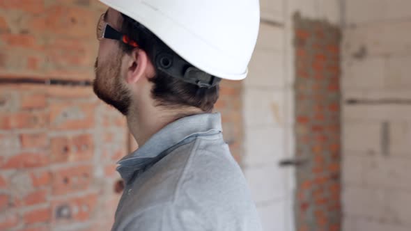 A man builder is studying a construction drawing at a construction site.