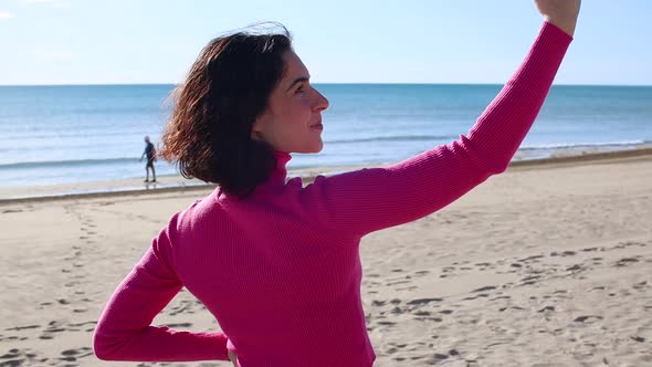 Young Woman Takes Pictures Using Smartphone Camera on the Beach