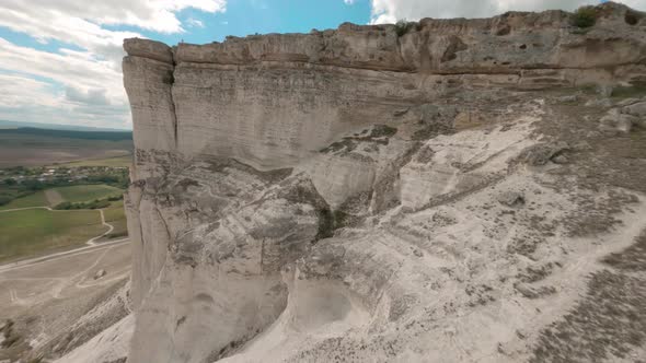 Freestyle Flight Dive Around Amazing Ancient Steep White Cliff Rising in Middle of Large Green