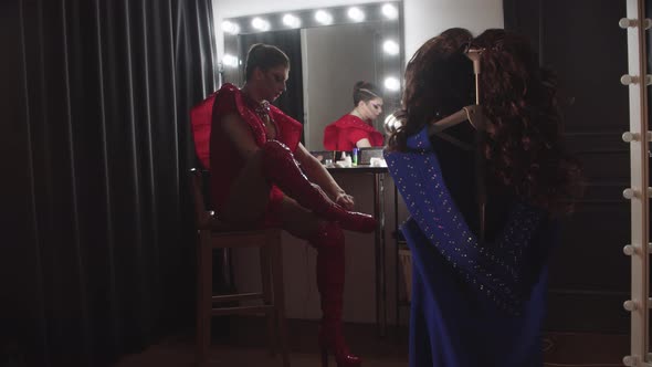 A Young Man Drag Artist Sitting in Front of the Mirror and Puts on High Heels