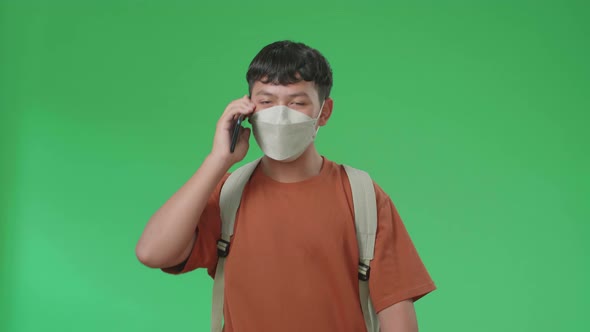 Asian Boy Student Wearing A Mask, Walking On Mobile Phone While Walking To School On Green Screen