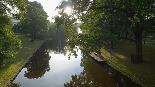 Gimbal Stabilized Tracking Shot of Park and The Riga Canal, Latvia, Warm Sun Rays Shine