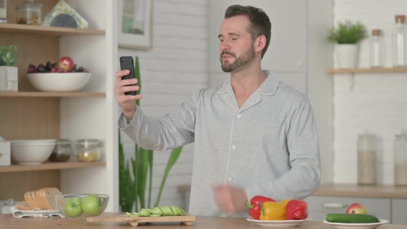 Young Man Talking on Video Call on Smartphone in Kitchen