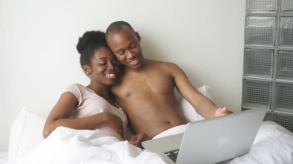 Positive Smiling Couple Watching Film on Laptop at Home.