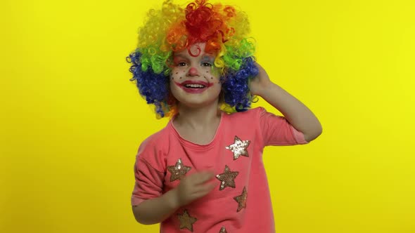 Little Child Girl Clown in Colorful Wig Tells Something Interesting. Having Fun, Smiling. Halloween